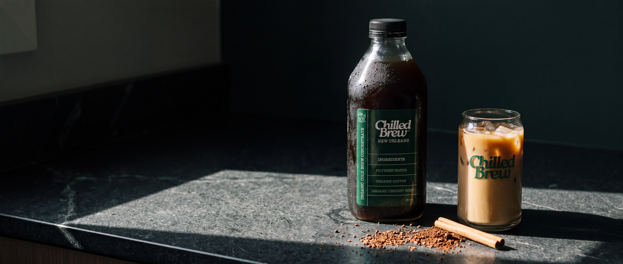 A bottle of New Orleans concentrate and a glass of iced coffee on a dark soapstone counter